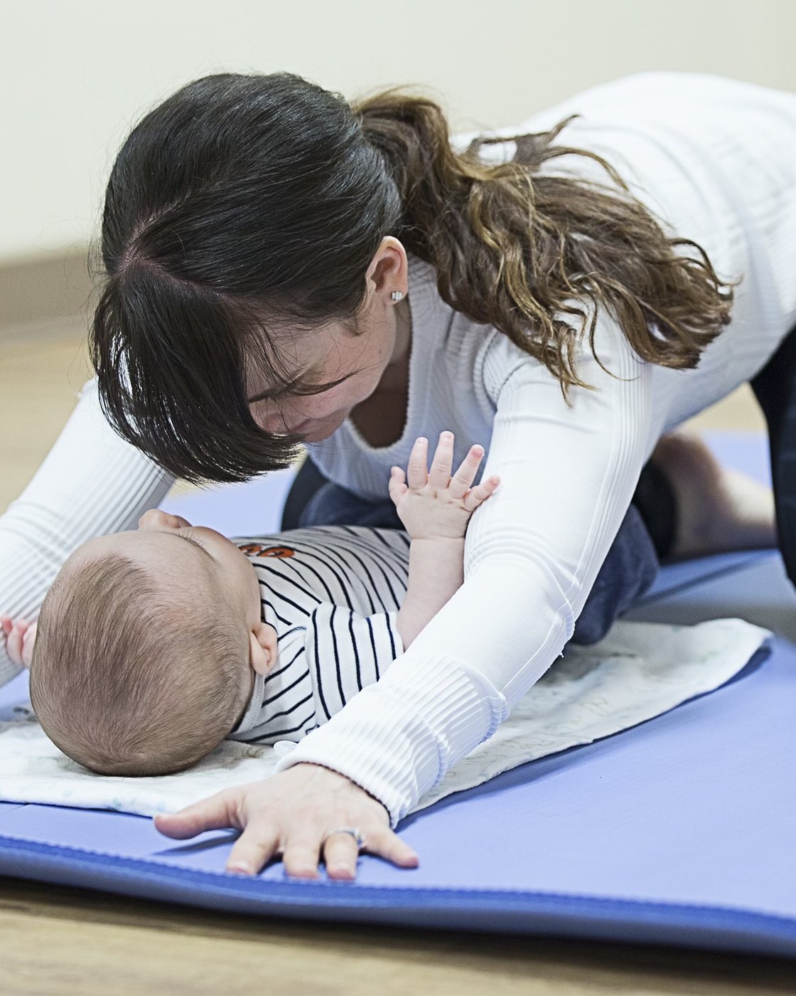 A mother on the mat with her baby during a postnatal physiotherapy session