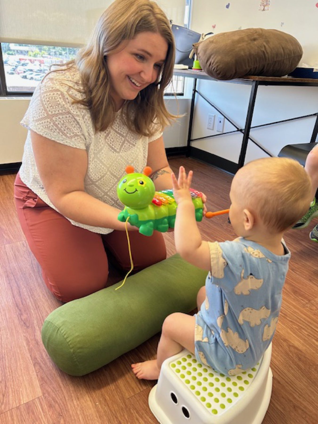 A physiotherapist offering a toy to a child during a pediatric physiotherapy session